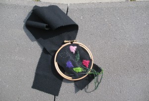 En rosa, lila och cerise blomma broderat på svart vadmal